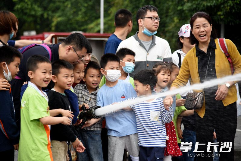 孩子们在家长的陪同下，体验消防水枪出水“灭火”。
