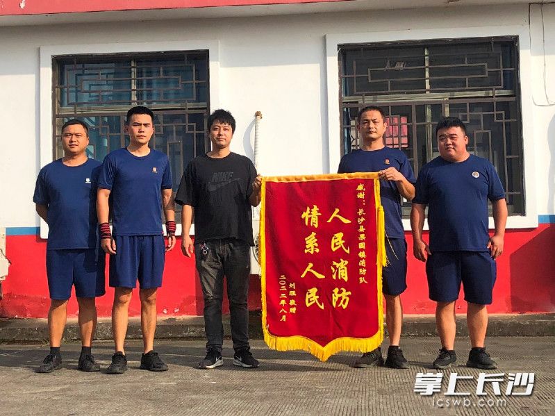 新明村居民刘旺将锦旗送至长沙县果园镇专职消防救援队，表达谢意。