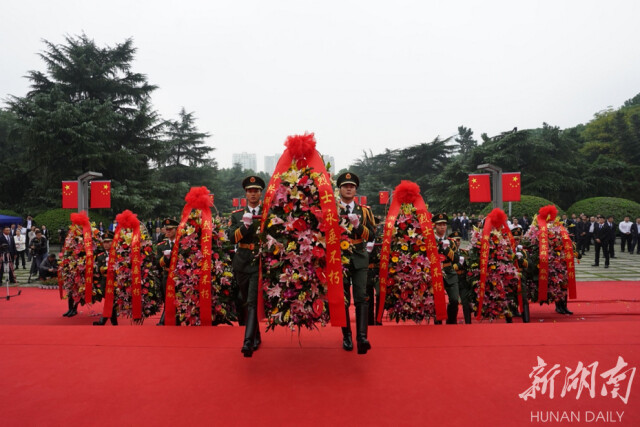 14名礼兵抬起花篮，将花篮敬放在烈士纪念塔前。