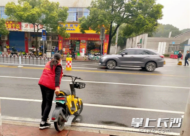 志愿者在街头清理随意摆放的共享电摩。