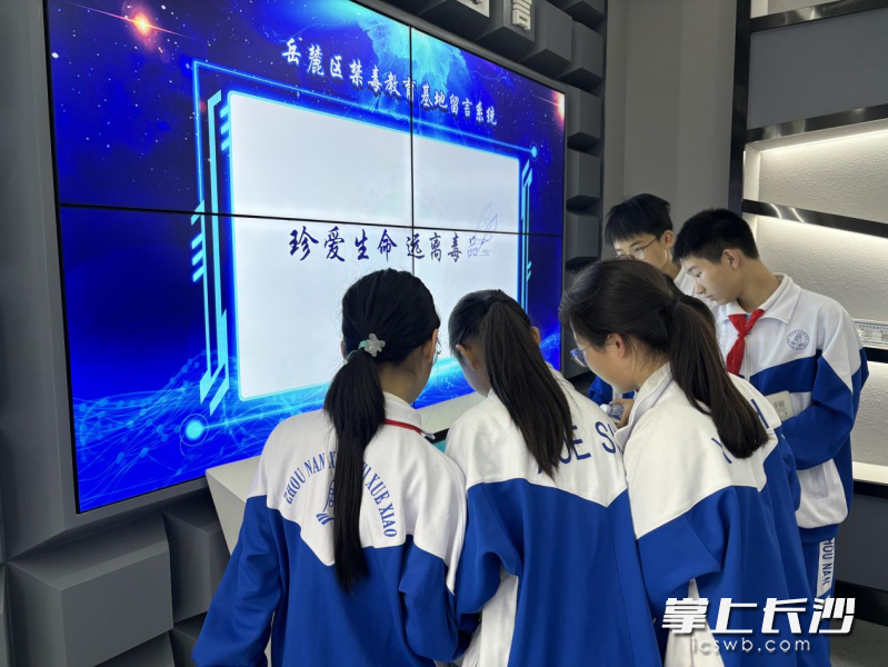 同学们通过触摸屏了解禁毒知识。