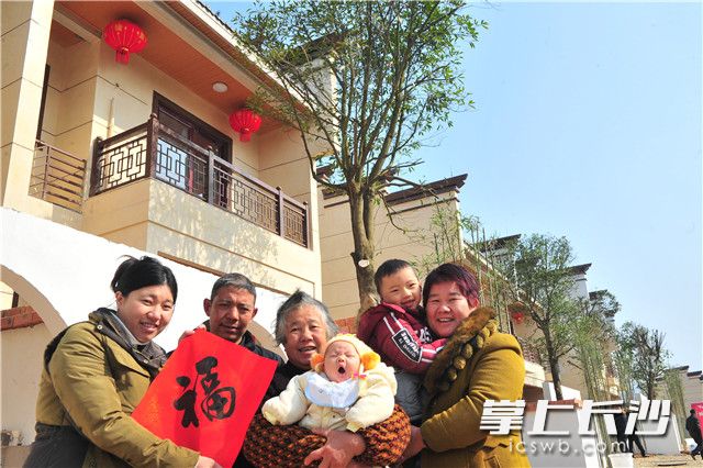 长沙县高桥镇易地扶贫搬迁项目白鹭湖生态小镇，罗忠海（左二）一家“拎包入住”温暖的新家，其乐融融拍摄全家福。长沙晚报全媒体记者 贺文兵 摄