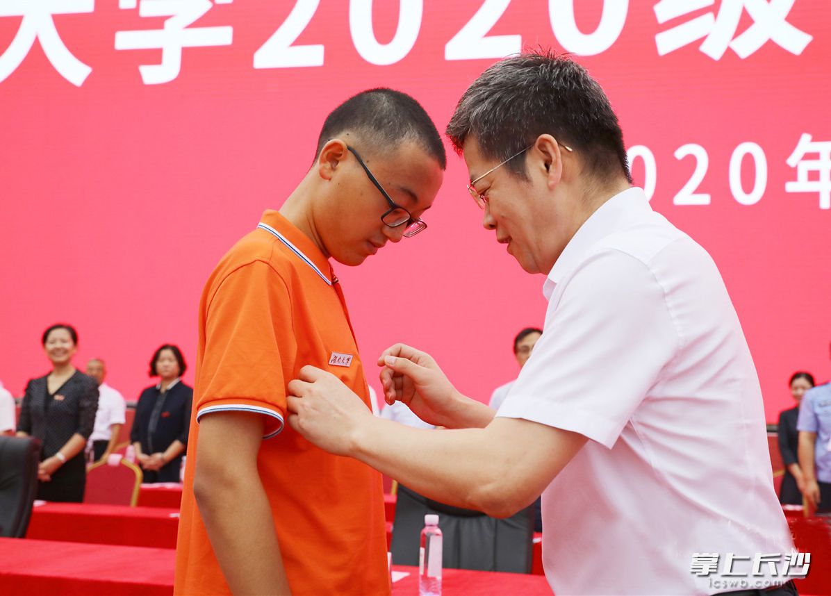 校党委书记邓卫为新生代表邓晗熙同学佩戴校徽。